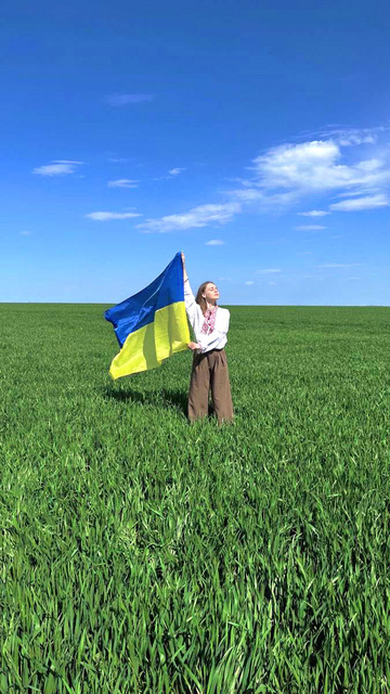 草原でウクライナ国旗を持つ女性.jpg